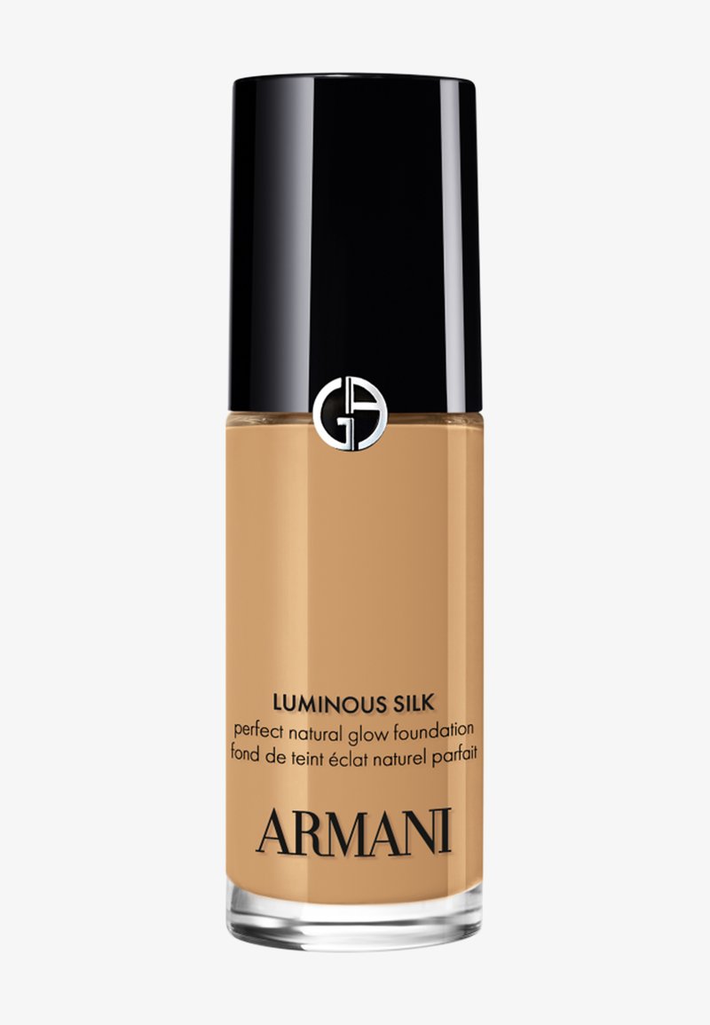 Flacon de fond de teint Armani Luminous Silk éclat naturel avec bouchon noir et logo sur un contenant transparent montrant un liquide beige à l’intérieur.