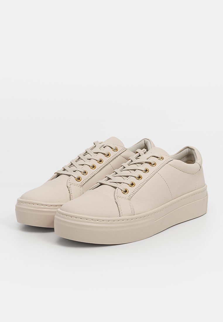 Beżowe sneakersy wykonane z gładkiej skóry, o zaokrąglonych czubkach, ze złotymi oczkami i wyściełaną podeszwą. Zaprojektowane w minimalistycznej sylwetce.