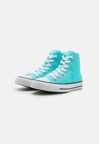 Sneakers alte in tela acquamarina con lacci bianchi, punta in gomma e striscia nera sulla suola. Presentano occhielli metallici e tessuto testurizzato.