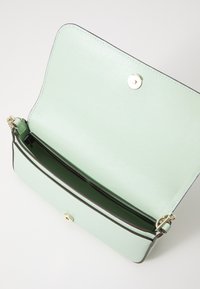 Light green, textured handbag with a snap closure. Interior features one zippered compartment, gold hardware, and a contrasting inner lining.