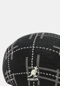 Cappello Kangol realizzato in tessuto a maglia con base nera e motivo a griglia bianca e grigia; toppa con logo raffigurante un canguro sul lato.