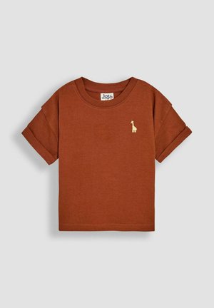 T-shirt kratkih rukava boje rđe napravljen od pamuka, s malim zlatnim vezom žirafe na lijevoj strani prsnog koša i klasičnim okruglim izrezom.
