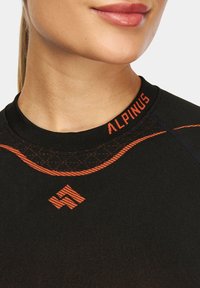 Czarny sportowy top z pomarańczowymi akcentami, w tym logo "ALPINUS" oraz dekoracyjnym przeszyciem wokół kołnierza i ramion.