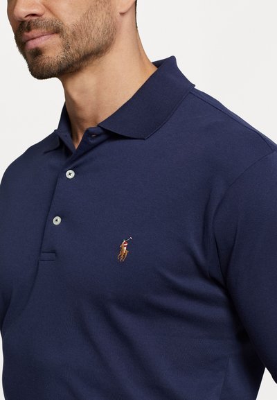 Jūras spēku polo krekls ar klasisku apkakli, trīs pogu aizdari un diskrētu logo izšuvumu kreisajā krūtī. Kokvilnas materiāls, gluda tekstūra.