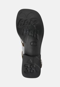 Juodas gumos padas su iškilmingu "CAM PER 38" ir logotipo dizainu. Yra lygi paviršius ir šiek tiek pakelta kulno forma.
