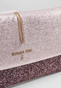 Gros plan d'une pochette rose et pailletée avec un détail en métal doré et le logo "Patrizia Pepe" sur la surface supérieure texturée.