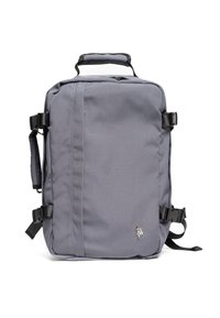 Šedý batoh vyrobený z odolné látky, má obdélníkový tvar, horní rukojeť, nastavitelné popruhy a na přední straně logo.