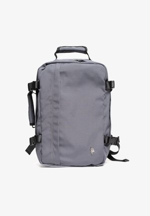 Zaino grigio realizzato in tessuto resistente, caratterizzato da una forma rettangolare, manico superiore, spallacci regolabili e un logo decorativo sulla parte anteriore.