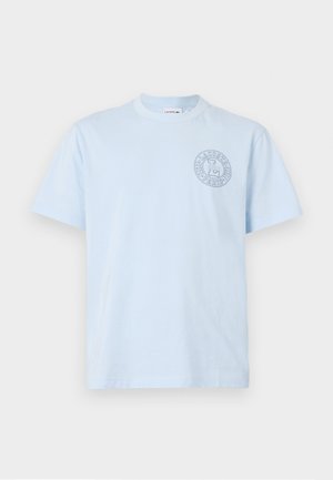Light blue cotton t-shirt with a round neck, short sleeves, and a circular logo featuring text and design accents on the left chest.
