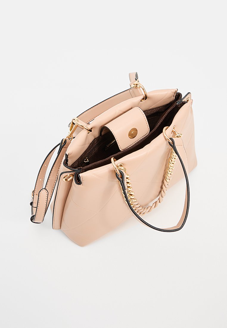Sac à main en cuir matelassé beige avec chaîne dorée et poignées en cuir, ouvert sur le dessus révélant une poche zippée intérieure et une fermeture à rabat magnétique.