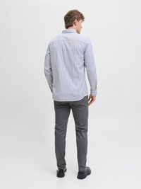 Srajca na gumb v modro-belih črtah, dolgi rokavi, ovratnik, skupaj s sivimi hlačami in črnimi čevlji. Gladek teksturiran material, prilagojen kroj.