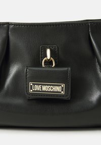Černá kožená kabelka s nařasenými detaily, vybavená zlatými kovovými akcenty a štítkem s nápisem "LOVE MOSCHINO." Hladká textura.