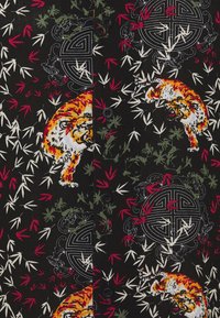 Maglietta nera a maniche corte con un motivo di tigri, foglie di bambù e disegni circolari in rosso, verde e bianco, con bottoni neri.