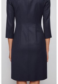 Marinblå klänning med skräddarsydd passform, med trekvartsärmar, rundad nederkant och subtilt texturerad tyg med vertikala sömmar.