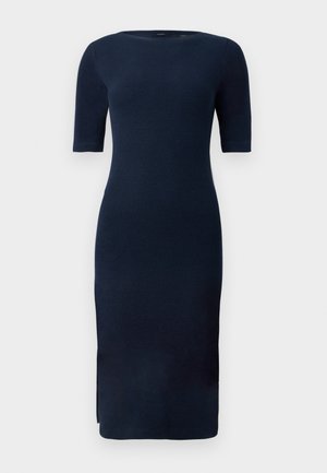 Tumši zila ceļgala garuma adīta kleita ar elkoņu garuma piedurknēm, apaļu izgriezumu un sānu šķēlumu uz viendabīga fona.