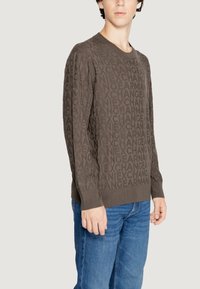 Maglione marrone con un motivo testurizzato della parola "CAMBIO" in uno stile ripetuto. Include maniche lunghe e colletto rotondo.