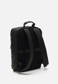 Zwarte rugzak van textuur faux leer met gaasaccenten, gevoerde schouderbanden, een handvat aan de bovenkant en een rechthoekige vorm. Beschikt over een ritsafsluiting.