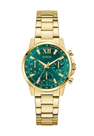 Montre bracelet en métal doré avec cadran vert, trois sous-cadres, échelle tachymétrique et marqueurs d'heure dorés, nom de la marque "GUESS" centré sous XII.