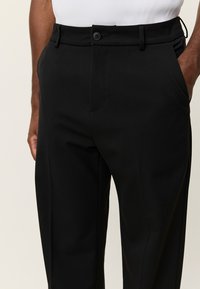 Μαύρο παντελόνι σε ίσια γραμμή, με μπροστινές τσέπες, κούμπωμα με κουμπί και απαλό, υφασμάτινο ύφασμα με υφή.