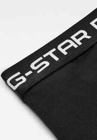 Mutande in cotone nero con un ampio elastico nero caratterizzato dal logo bianco "G-STAR". Il tessuto è morbido e leggermente elasticizzato.