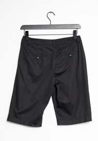 Shorts noirs arrivant aux genoux, en tissu léger, présentant une texture lisse, deux poches arrière avec des accents de bouton et une coupe droite.