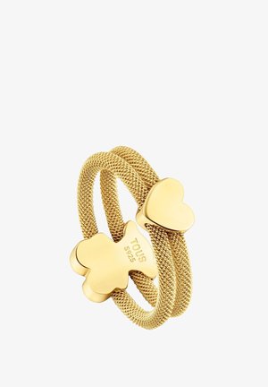 Bague double bande de couleur dorée avec une texture tissée, ornée d'un ours en peluche et d'accents en forme de cœur. Logo de la marque gravé visible.