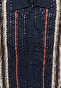 Cardigan en maille bleu marine avec des rayures verticales beige et orange, boutonné sur le devant et col pointu.
