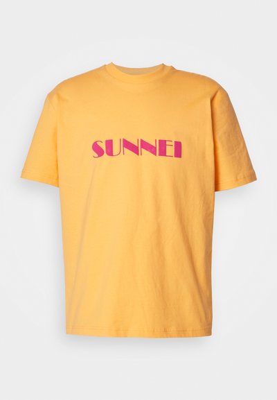 Gul bomull T-skjorte med korte ermer, med ordet "SUNNEI" i fete rosa bokstaver på tvers av brystet. Rund halsdesign.