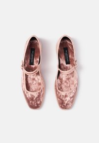 Par de bailarinas Mary Jane de terciopelo rosa con correas de hebilla y plantillas negras etiquetadas "SCAROSSO HECHO EN ITALIA" sobre un fondo blanco.