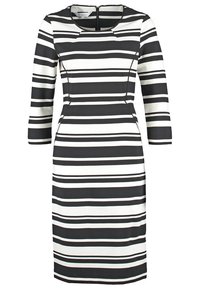 Robe rayée horizontale noire et blanche longueur genou avec manches trois-quarts et encolure ronde, avec une silhouette cintrée.