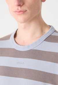 Strandede bomulds t-shirt med lyseblå og brune horisontale striber, rund halsudskæring og subtilt præget logo på brystet.