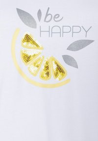 Hvid t-shirt med et design af en citronskive i gule paljetter, med teksten "vær GLAD" i grå og grønne blade.