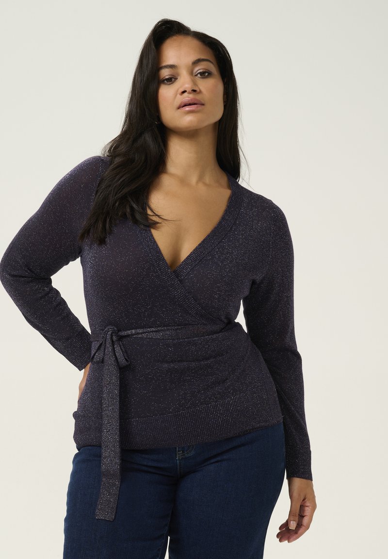 Suéter envolvente de color navy en punto suave, con un escote en V profundo, mangas largas y una cintura ajustable con lazo. Sutil brillo en toda la tela.