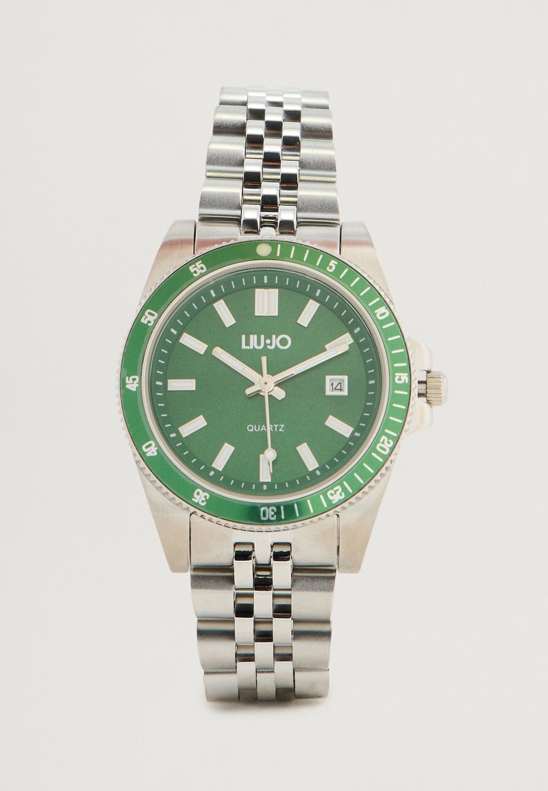 Ceas din oțel inoxidabil argintiu cu un cadran verde, mecanism quartz, marcaje orare argintii, afișaj al datei și o bratara metalică cu zale.