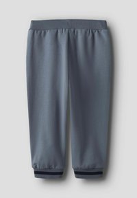 Pantalon de survêtement gris avec taille élastique et finitions côtelées, arborant une seule bande sombre, posé à plat sur un fond clair.