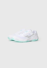 White athletic shoes with mesh fabric and silver accents. The sole is light turquoise with textured grip patterns. Laced design.
