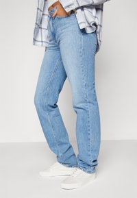 Ljusblå jeans i denim med rak passform, med synliga sömmar, knappgylf och subtila whiskeringdetaljer.