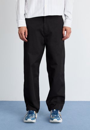 Black trousers with a straight-leg design, made from a smooth fabric. Paired with blue athletic shoes featuring a mix of textures and colors.
