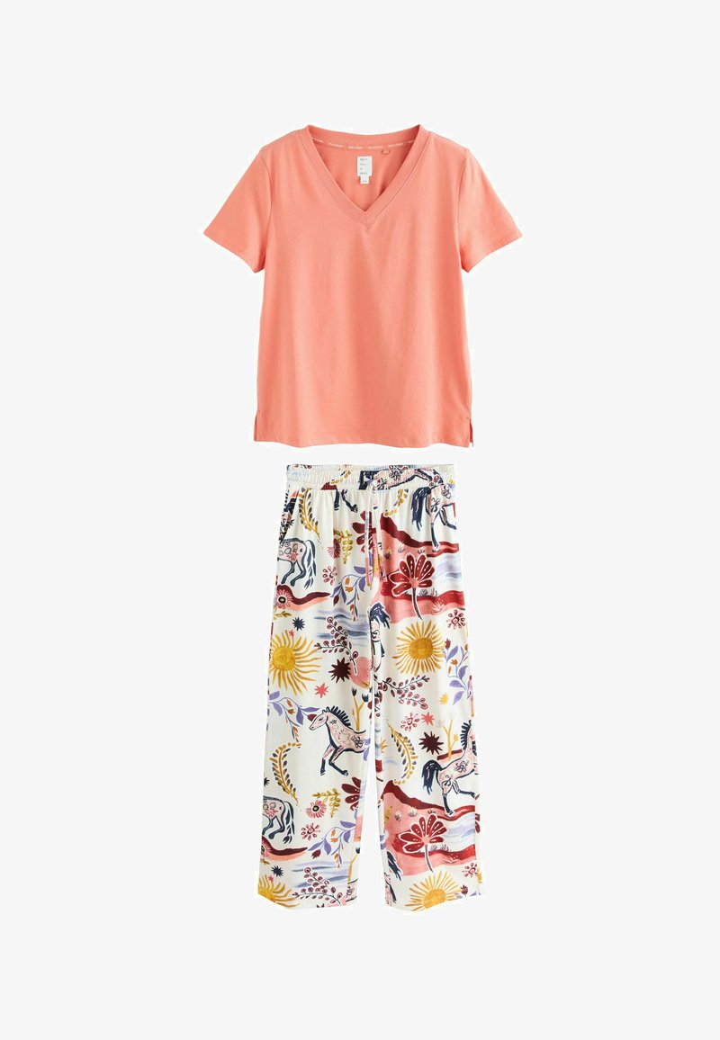 Koraalrode T-shirt met V-hals en korte mouwen met zijsplitten, gecombineerd met witte broek met kleurrijke eenhoorn- en bloemenpatronen.