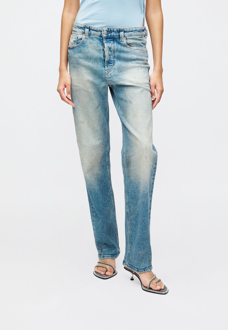 Svijetloplave traperice s opuštenim krojem, izblijedjelim završetkom i suptilnim oštećenjima; oblikovane s strukom srednje visine i klasičnim dizajnom s pet džepova.