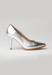 Zapato de tacón alto plateado con punta afilada, acabado metálico suave y un tacón de aguja esbelto, que presenta una suela de goma color marrón.