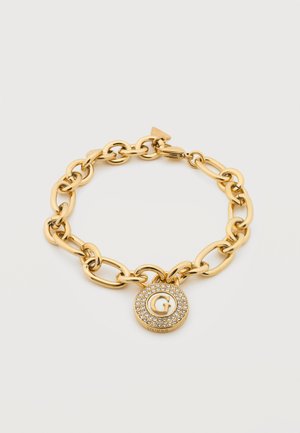 Bracelet chaîne en or avec de gros maillons et un pendentif rond orné d'un "G" entouré de petits cristaux clairs.
