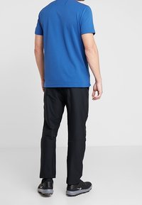 Modrý polo tričko s krátkým rukávem v kombinaci s černými lehkými kalhotami. Oblečení má pohodlný střih a jemné švy.