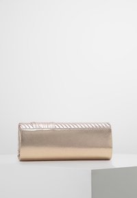 Metallisk guldig clutch med en texturerad, veckad topp och en slät yta, med rektangulär form och minimalistisch design.