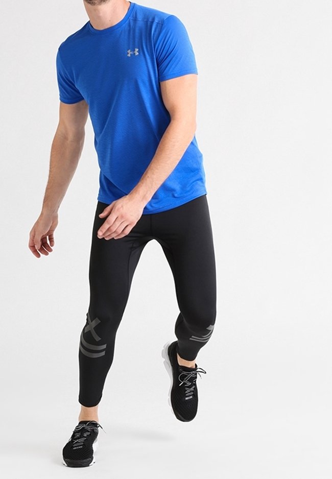 Camisa atlética azul con un acabado texturizado, leggings ajustados negros con acentos grises y zapatillas deportivas negras con diseño de cordones.