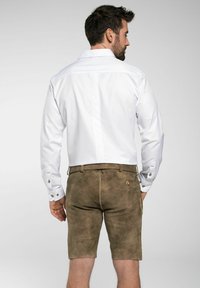 Witte overhemd met lange mouwen en knoopmanchetten, gecombineerd met bruine leren shorts, die een gestructureerde afwerking en een getailleerde pasvorm tonen.