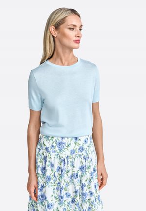 Top de manga corta azul claro con cuello redondo, combinado con una falda de estampado floral que presenta flores azules sobre un fondo blanco.