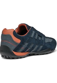 Granatowe sneakersy z elementami z zamszu i siateczki, pomarańczowymi akcentami oraz czarną gumową podeszwą z wystającymi bieżnikami dla lepszej przyczepności.