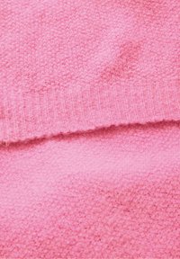 Kahvatu roosa kudumkangas ribade servaga, millel on pehme tekstuur ja ühtlane värv kogu pinna ulatuses.