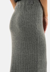 Falda de punto acanalado gris que presenta una silueta ajustada, textura suave y una cintura alta con líneas verticales para mayor elasticidad.